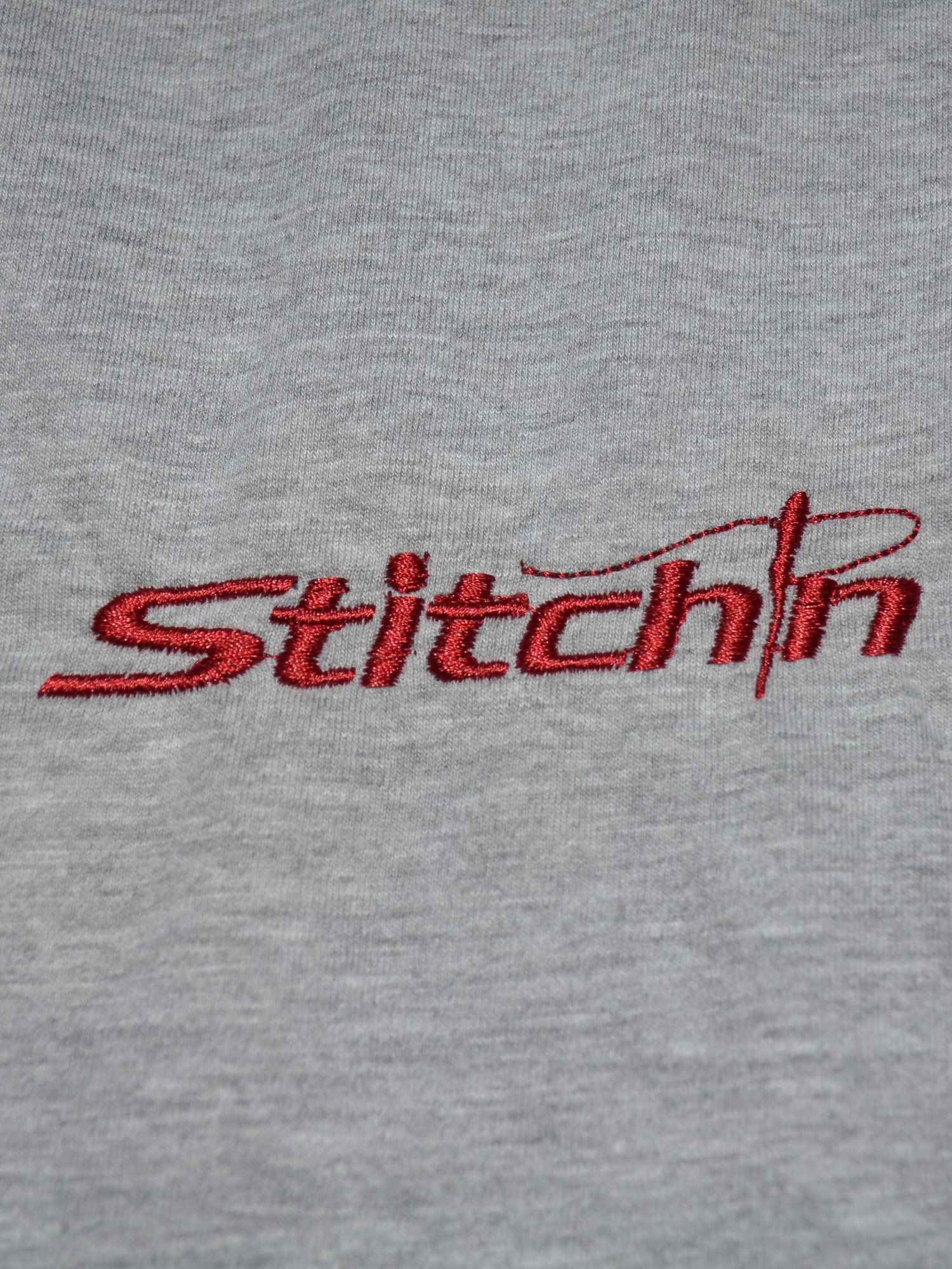 Qualitätskontrolle: das rot gestickte Stitchin-Logo auf dem grauen Shirt